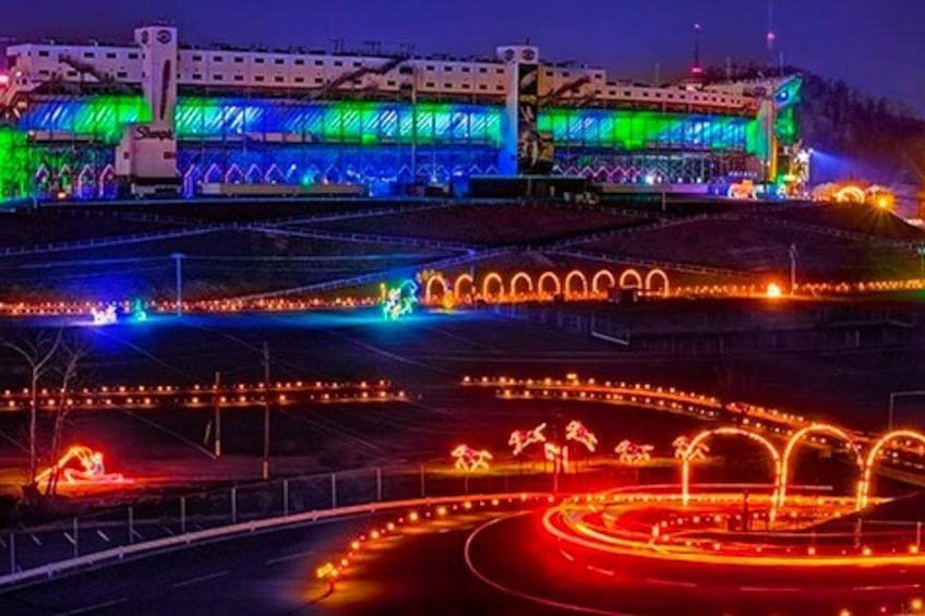 A brightly lit stadium with colorful lights and a road with light trails. 2