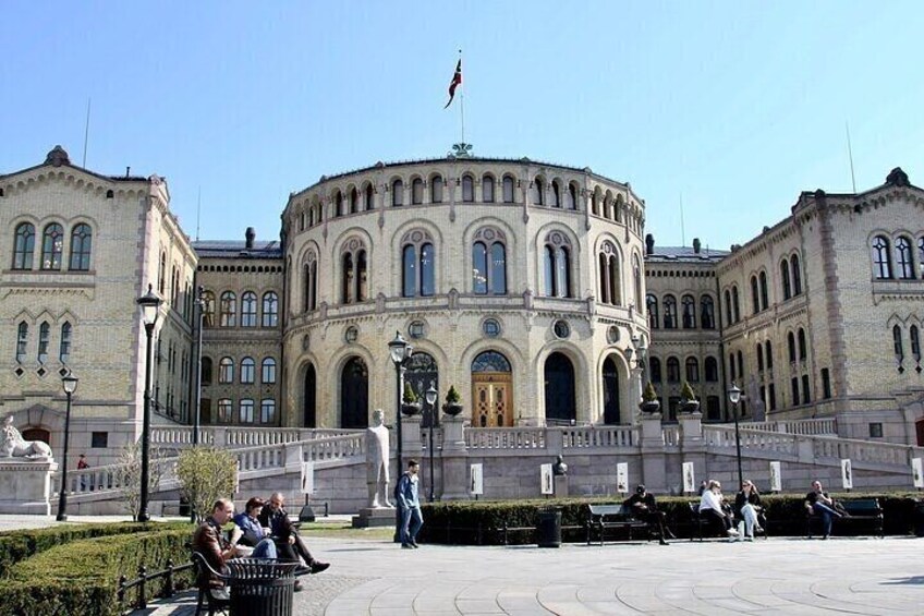 A historic building with arched windows and a central dome, surrounded by a plaza with benches and people. 4