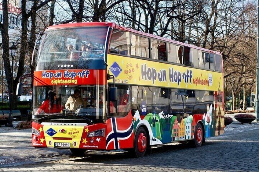 A double-decker bus with colorful advertisements and the text "Hop on Hop off sightseeing" on its side. 1