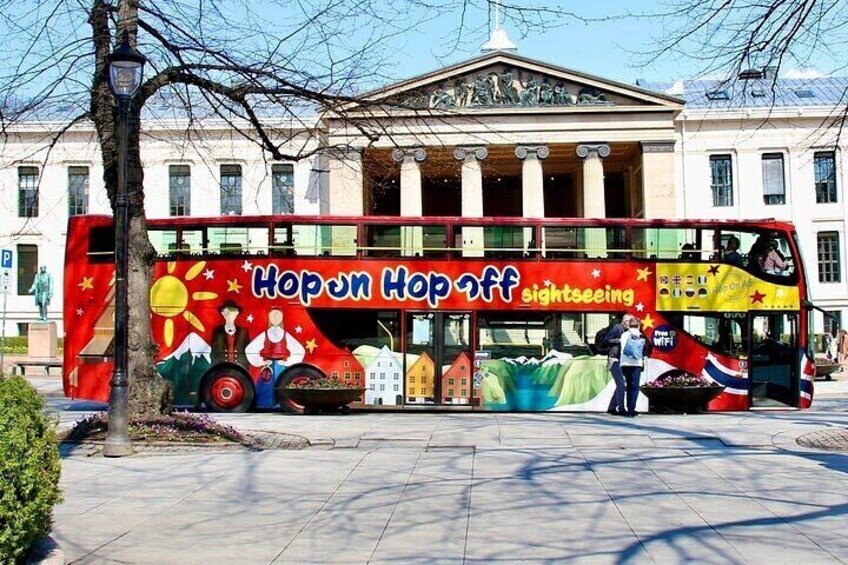 A red double-decker bus with a colorful mural advertising a hop-on hop-off sightseeing service. 5