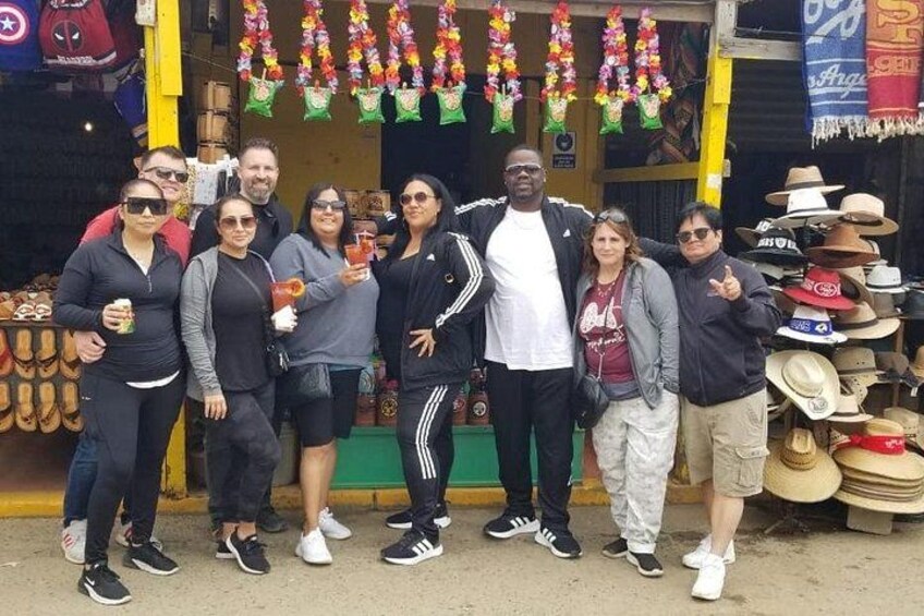 A group of people standing in front of a store with hats and colorful decorations. 3