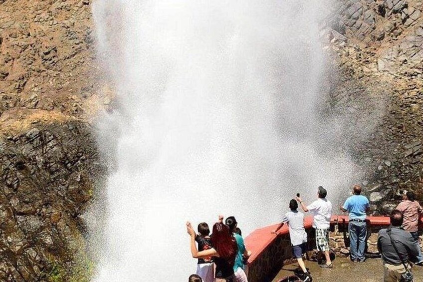 A group of people observing a waterfall. 1