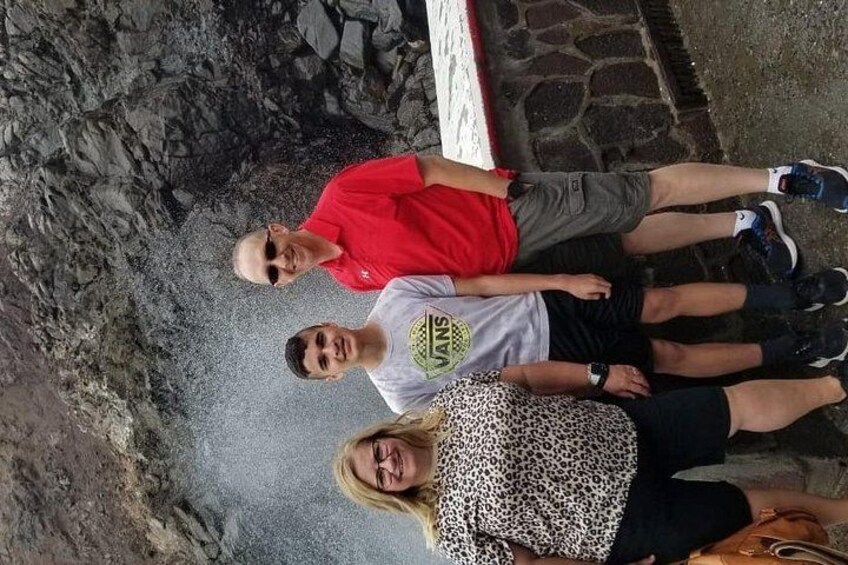 Three people standing on a rocky terrain with a stone wall in the background. 2