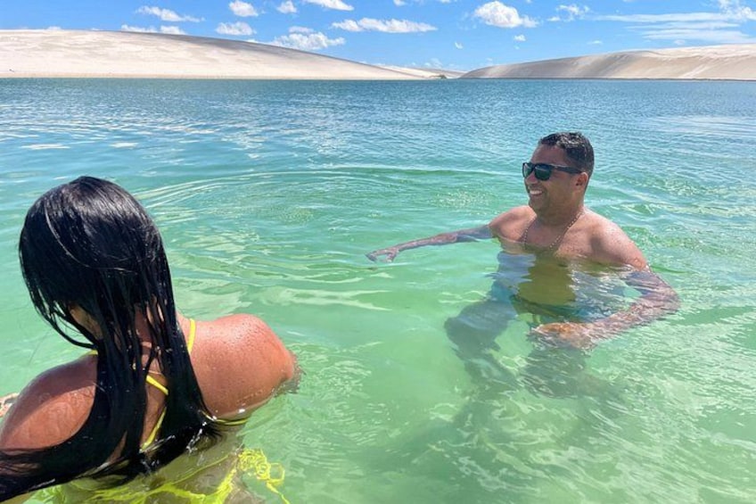 Two people in clear water with a desert landscape in the background. 3