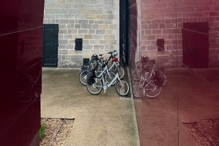 A courtyard with a brick wall, a black door, and bicycles parked against the wall. 1