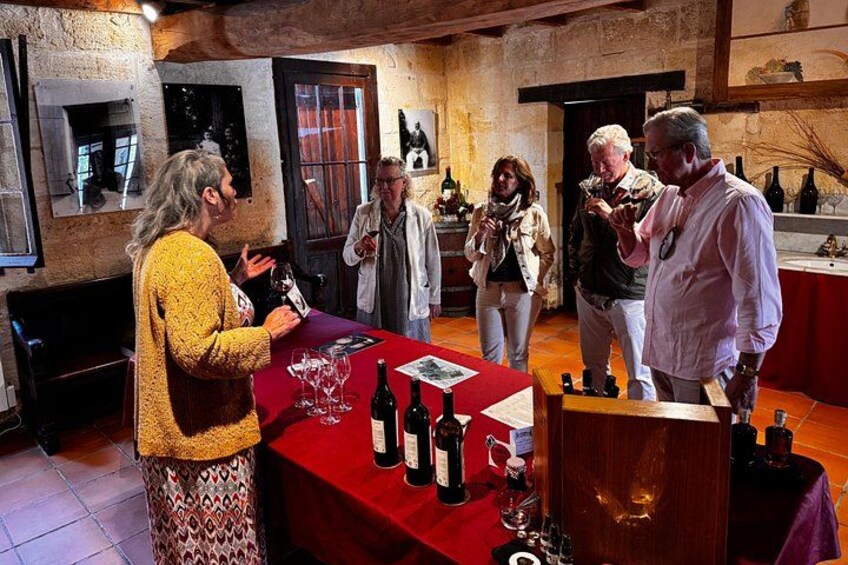 Un grupo de personas en una degustación de vinos en una sala rústica con vigas de madera y paredes de piedra. 5
