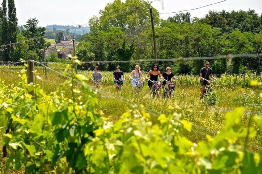 Un groupe de personnes fait du vélo dans un champ herbeux, avec des arbres et un bâtiment en arrière-plan. 1