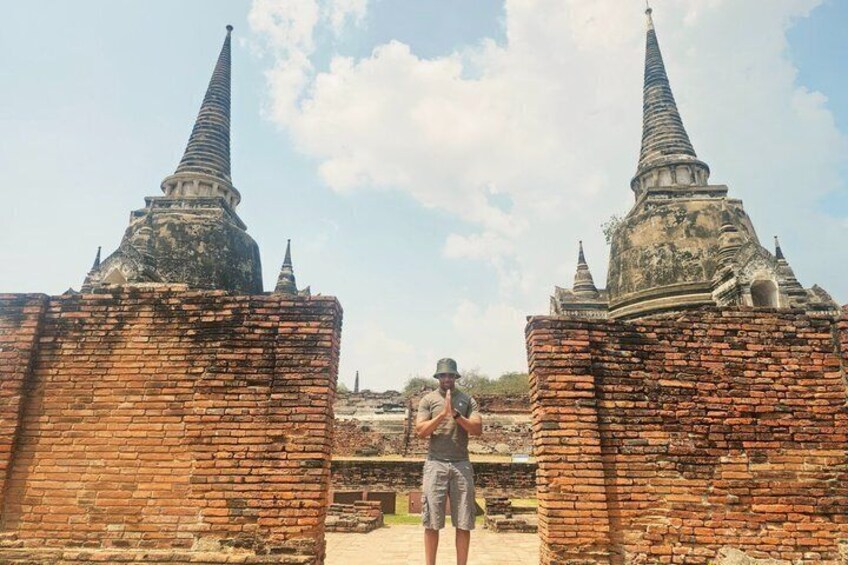 A person taking a photo with two brick structures and pointed roofs in the background. 2