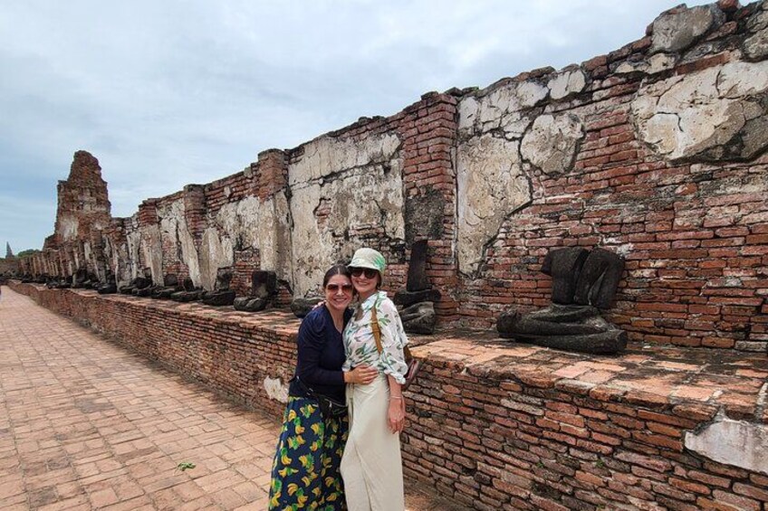 A historical brick wall with stone statues and a paved walkway. 3