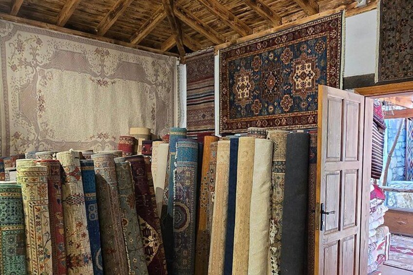 A collection of rugs displayed in a room with wooden beams on the ceiling. 2