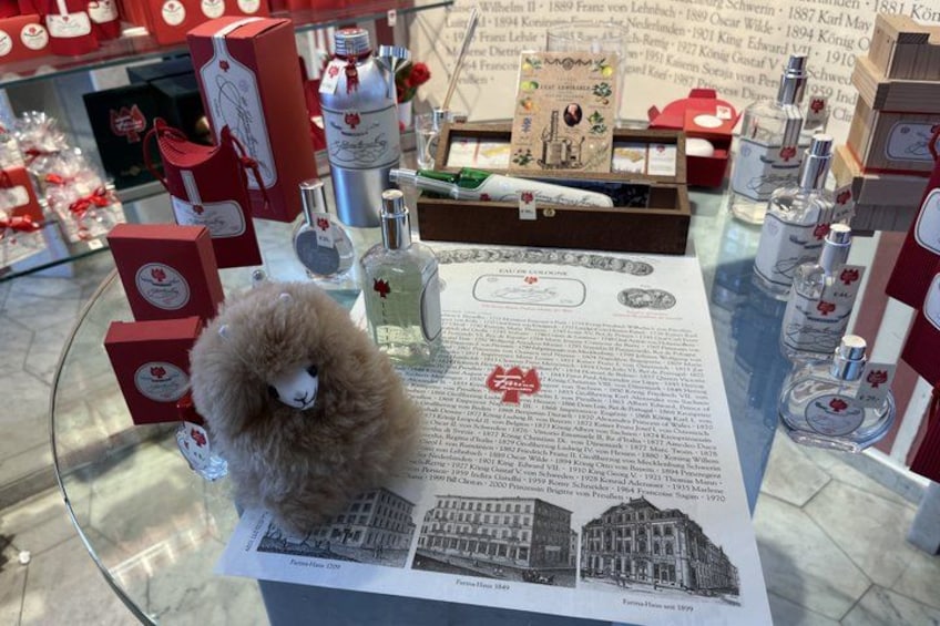 A glass display table with a plush toy, perfume bottles, and red boxes. 2