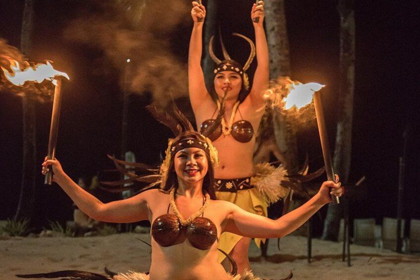 Deux personnes exécutent une danse avec des torches enflammées, vêtues de costumes traditionnels, sur une plage, de nuit. 4