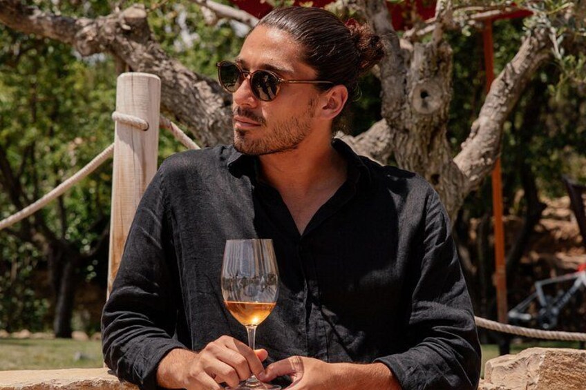 A person sitting outdoors holding a glass of wine. 3