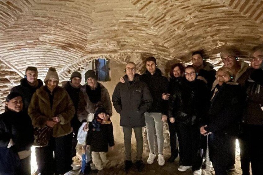 Een groep mensen in een stenen, ondergronds vertrek. 3