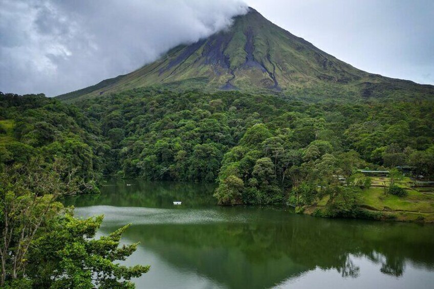 A lake surrounded by lush greenery and a mountain with a visible crater. 3