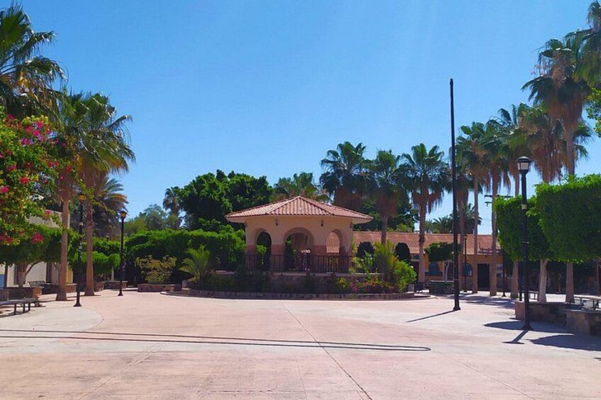 A courtyard with a building featuring arches, palm trees, and a clear blue sky. 3
