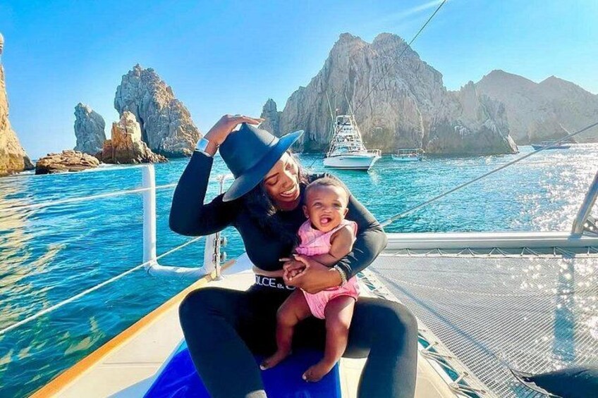 A boat with a person and a child, rocky cliffs, and clear blue water. 2