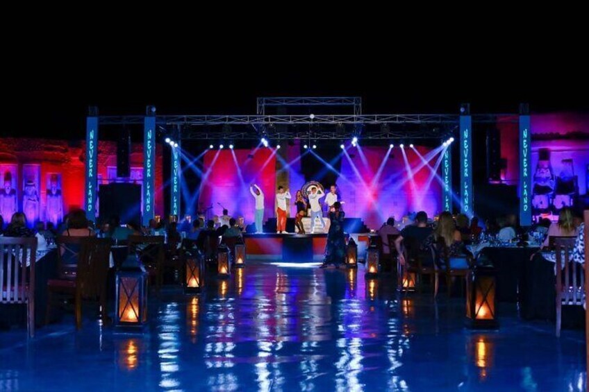 A stage with performers, audience, and decorative lighting. 4