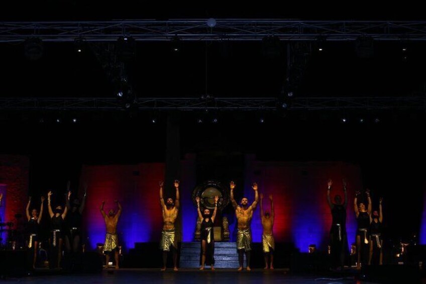 A stage with performers in golden costumes, a staircase, and a dark background. 5