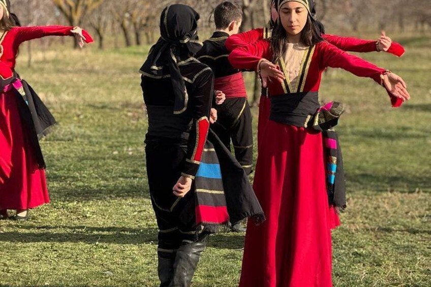 People in traditional costumes performing a dance in an open field. 4