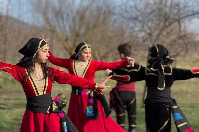 People in traditional attire performing a dance in an open field. 3