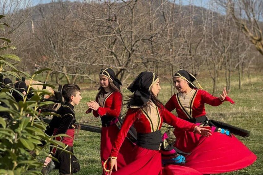 A group of people in traditional costumes, possibly reenacting a historical event, in an outdoor setting with trees and grass. 2