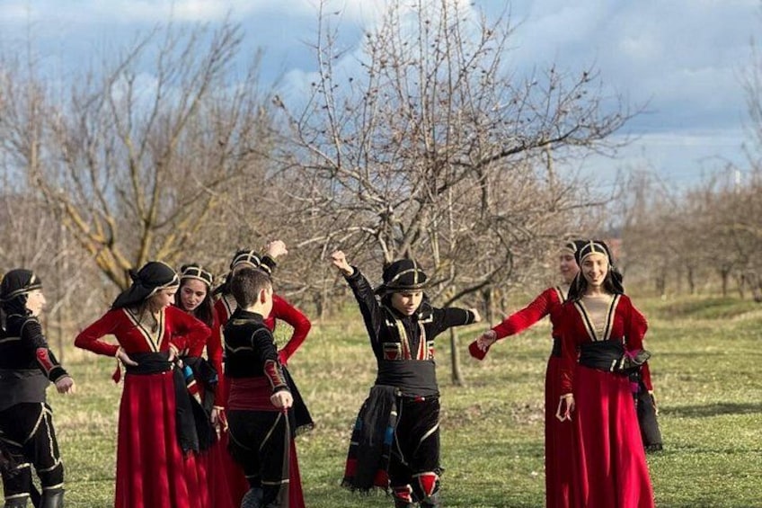 A group of people in historical costumes, standing in a grassy field with bare trees in the background. 5