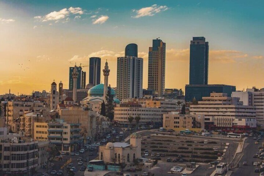A cityscape with tall buildings, a mosque with a green dome, and a busy street. 2