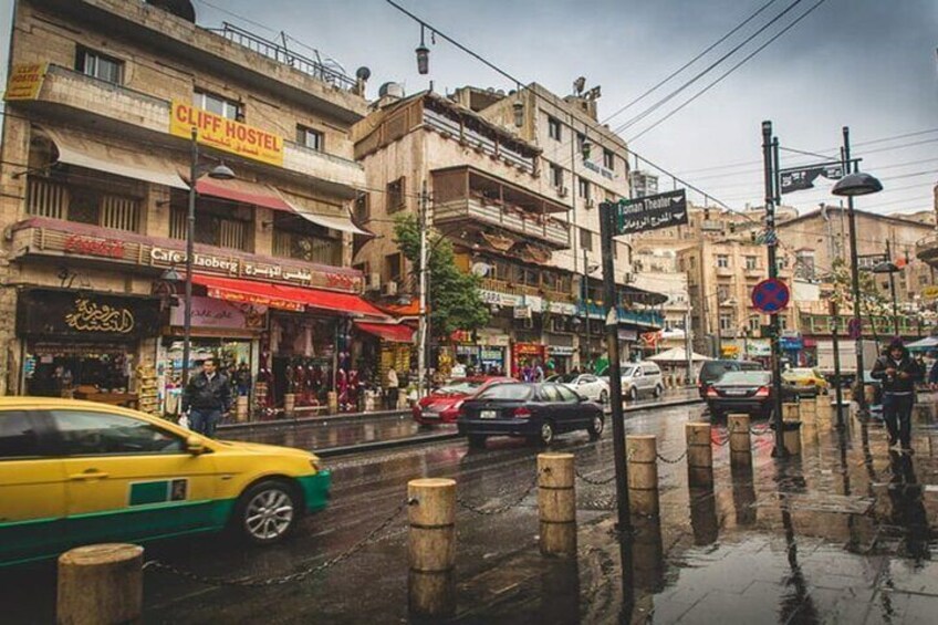A busy street with a yellow taxi, wet pavement, and buildings with signs like "Cliff Hostel" and "Cafe". 5