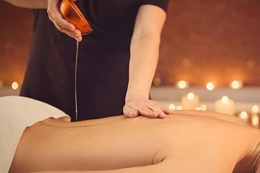 Een persoon ontvangt een massage, er wordt olie over de rug gegoten. 1