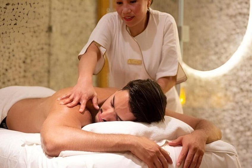 Iemand ontvangt een massage in een wellnessruimte, met een structuurwand en een ronde lamp. 5