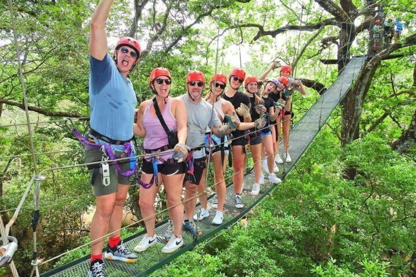 A group of people on a suspended zipline in a forested area. 3