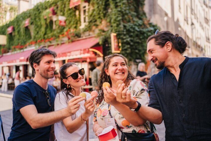 A group of people standing on a street, holding food items. 4