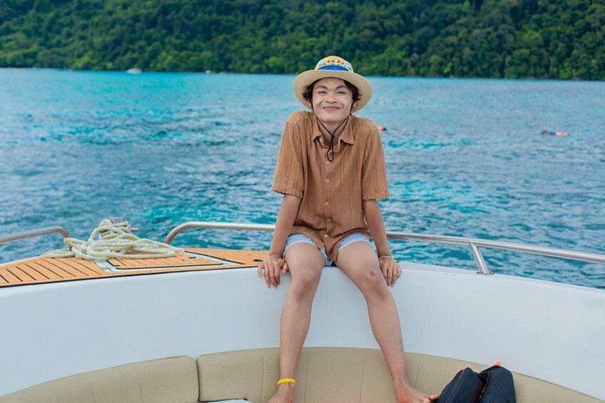 A person sitting on a boat with a forested island in the background. 5