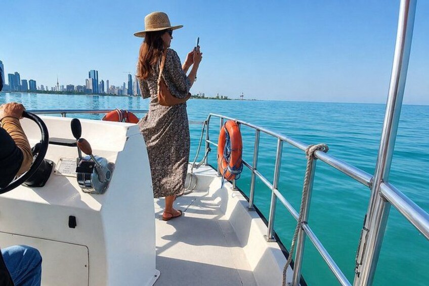 A woman on a boat, a city skyline in the background, and calm blue water. 4