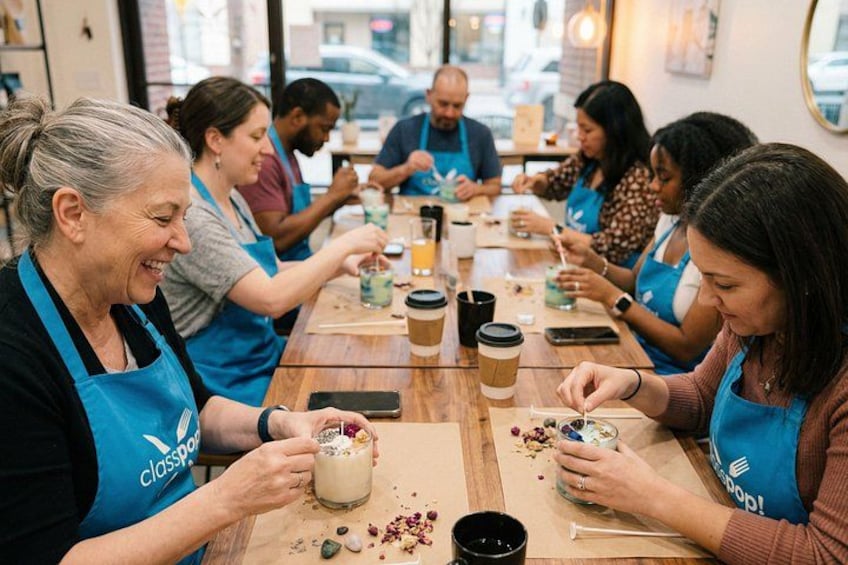 Un grupo de personas con delantales azules participando en un taller o clase, con tazas de café y una mesa de madera. 2
