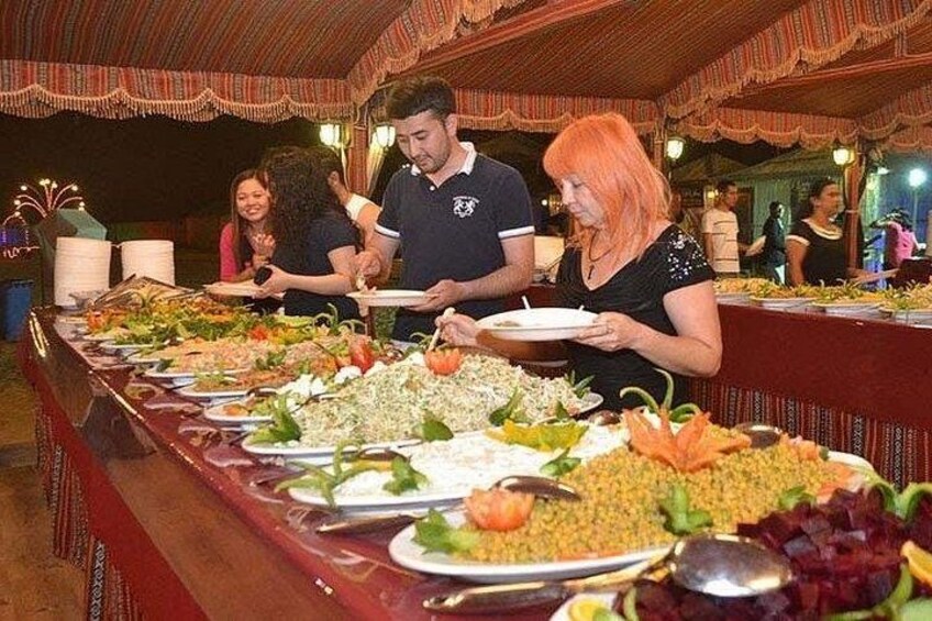 A buffet with various dishes, including salads and grains, in a covered dining area. 2