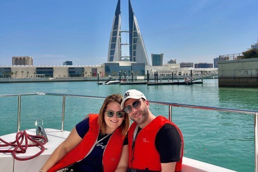 A boat with two people wearing life jackets, a bridge, and calm water. 4