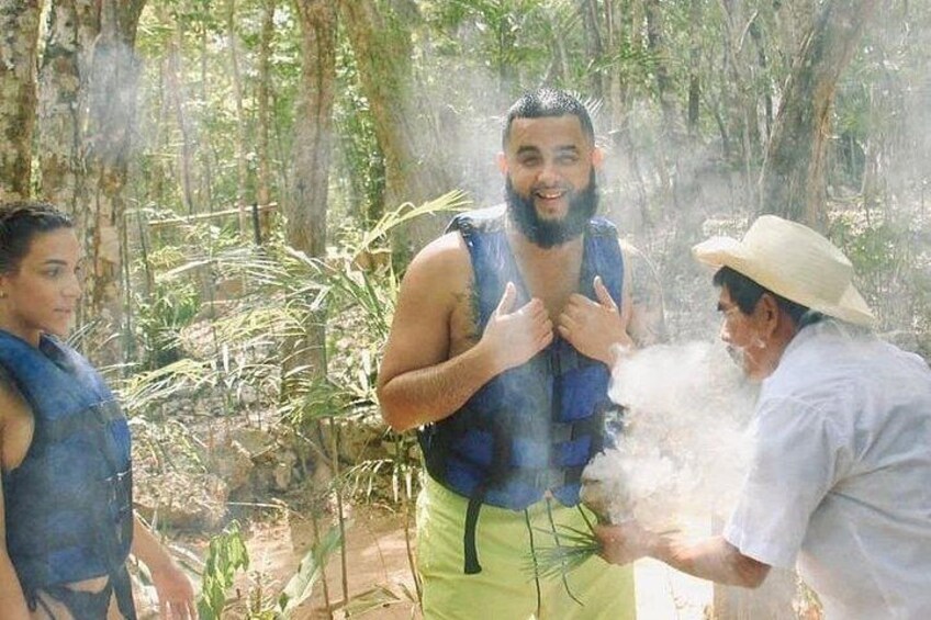 Una persona con chaleco azul y pantalones cortos verdes en un área boscosa, otra persona con sombrero y una tercera persona con camisa azul. 4