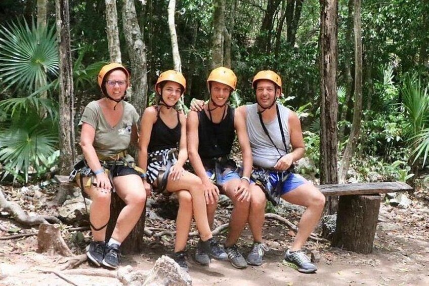 Cuatro personas con cascos sentadas sobre un tronco en un bosque. 3