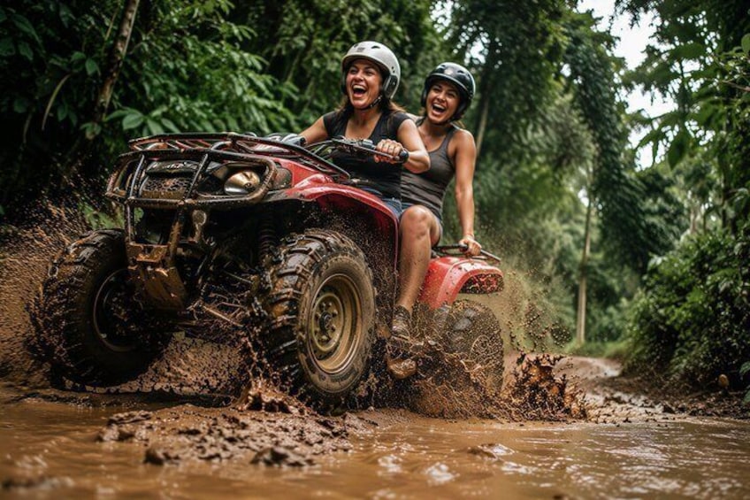 Dos personas conducen un cuatrimoto rojo por un sendero embarrado en un bosque. 1