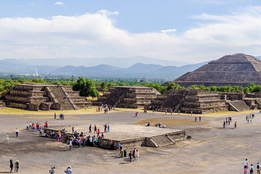 Ein weitläufiges archäologisches Gelände mit mehreren Pyramiden und einem großen, offenen Platz. 1