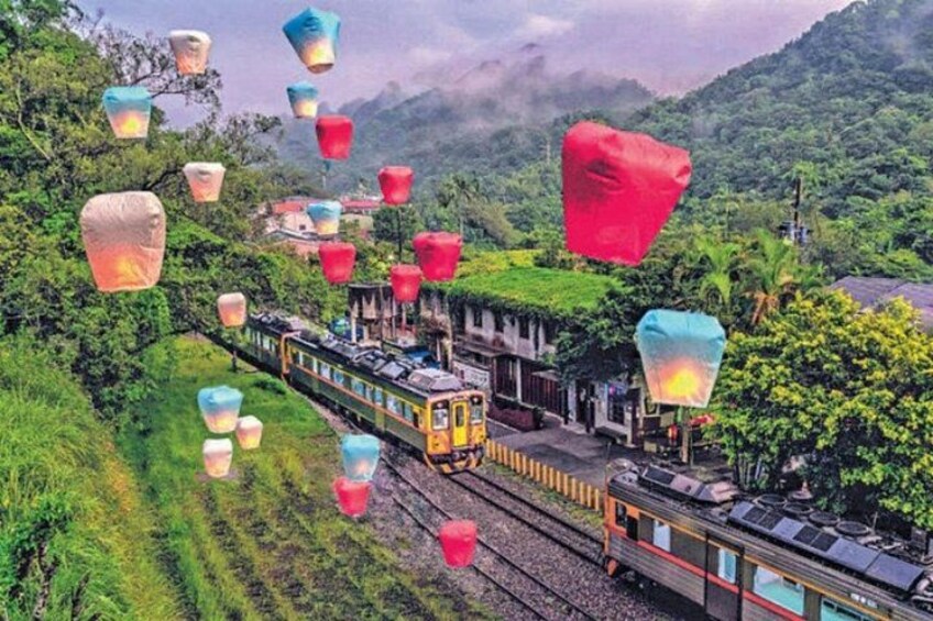 A train on tracks with colorful lanterns floating above. 3