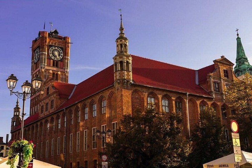 A historic building with a clock tower, a red roof, and a green spire. 1