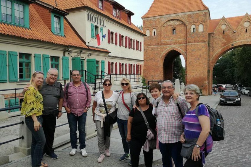 A group of people standing in front of a hotel and a historic archway. 3