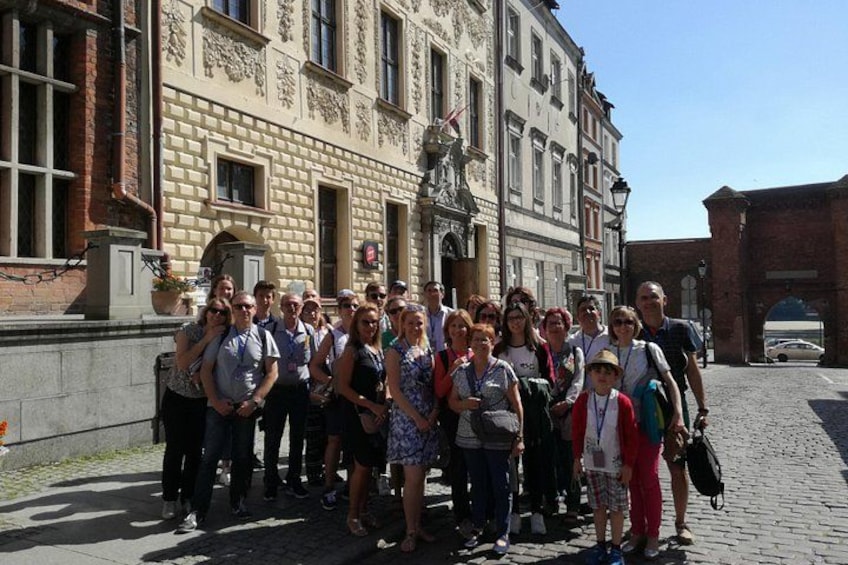 A group of people standing in front of a historic building with a statue and an archway. 5