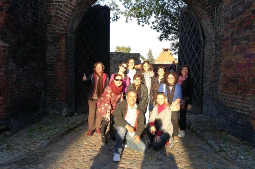 A group of people posing in an old brick building with arched doorways. 4