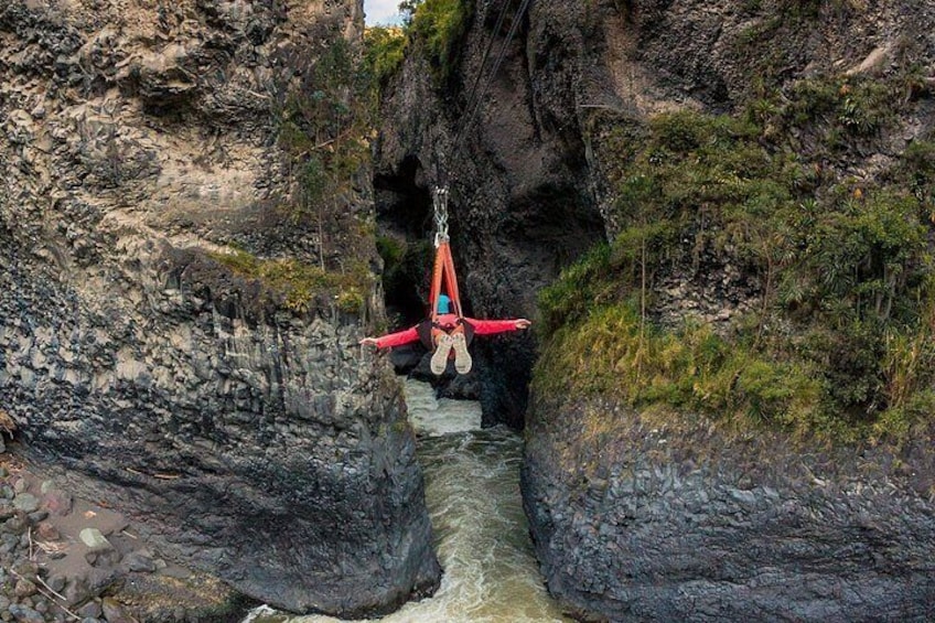 A person suspended in mid-air by a harness, with a red parachute, in a rocky gorge. 4
