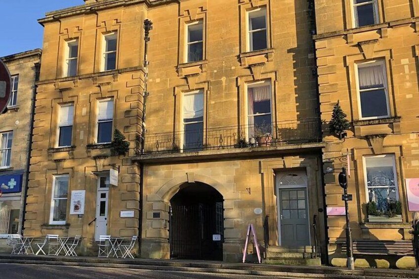 A historic building with a large arched entrance, multiple windows, and a signboard. 2