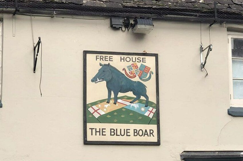 A wall with a sign for 'The Blue Boar' pub, featuring a horse and a flag. 3
